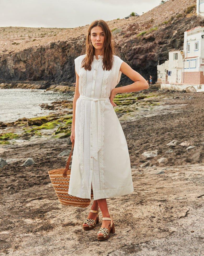 Woman at beach in white broderie dress